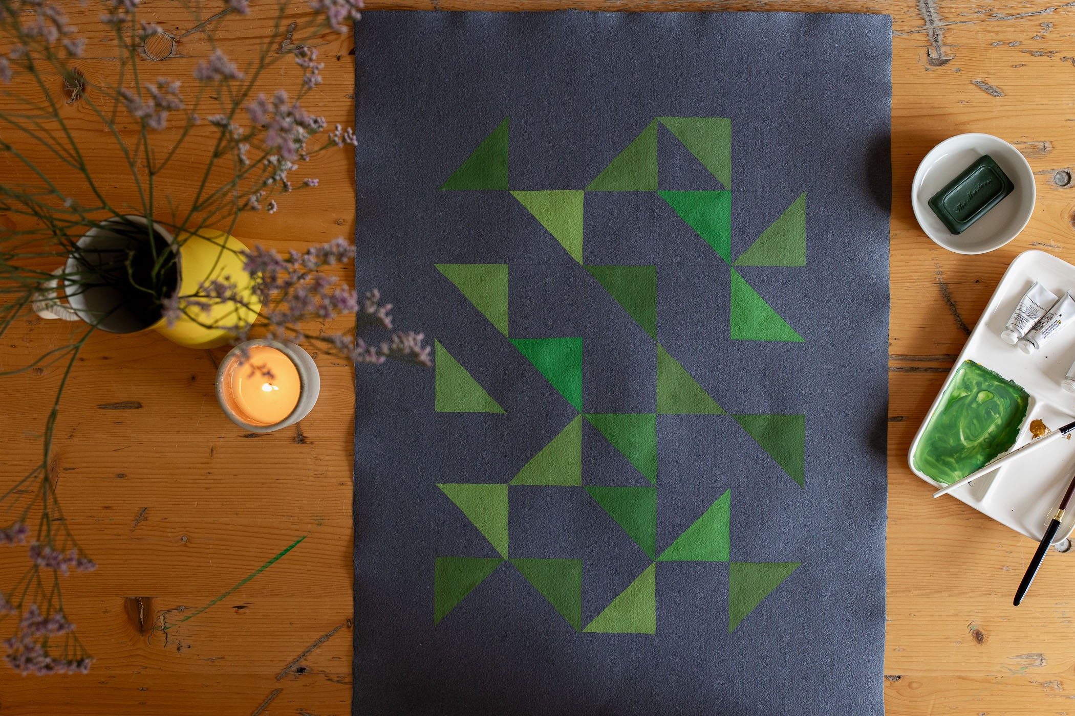 guache painting of green triangles on dark paper