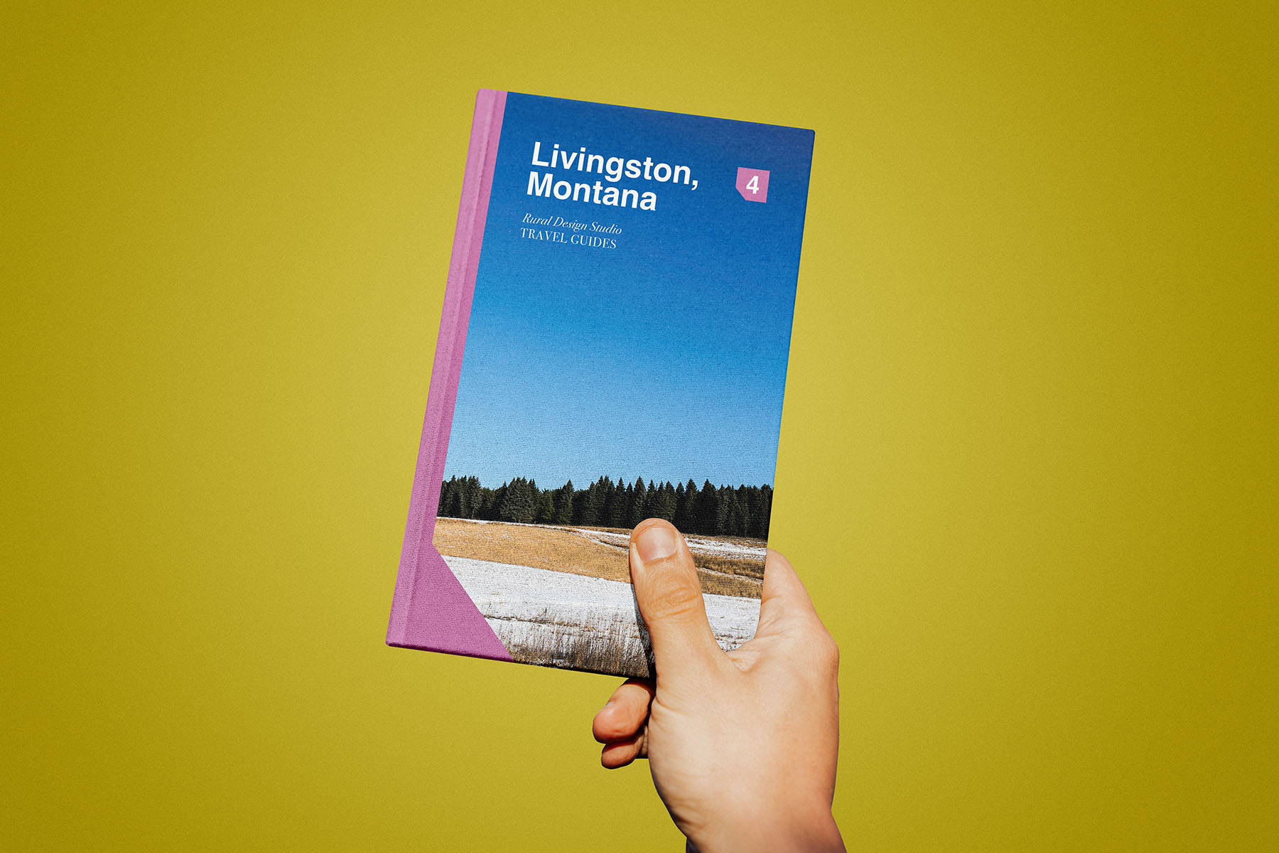 Guidebook prototype being held by a hand against a yellow background